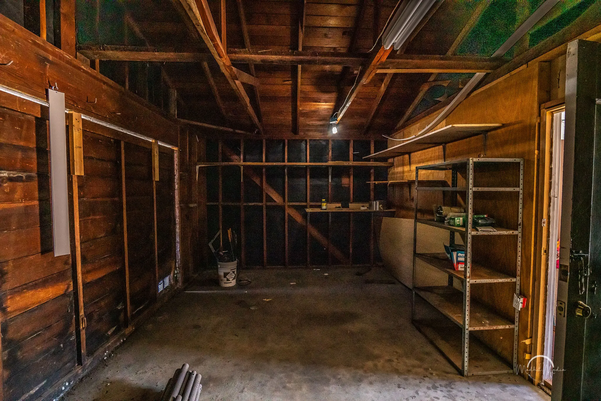 Empty wooden garage with metal shelves.