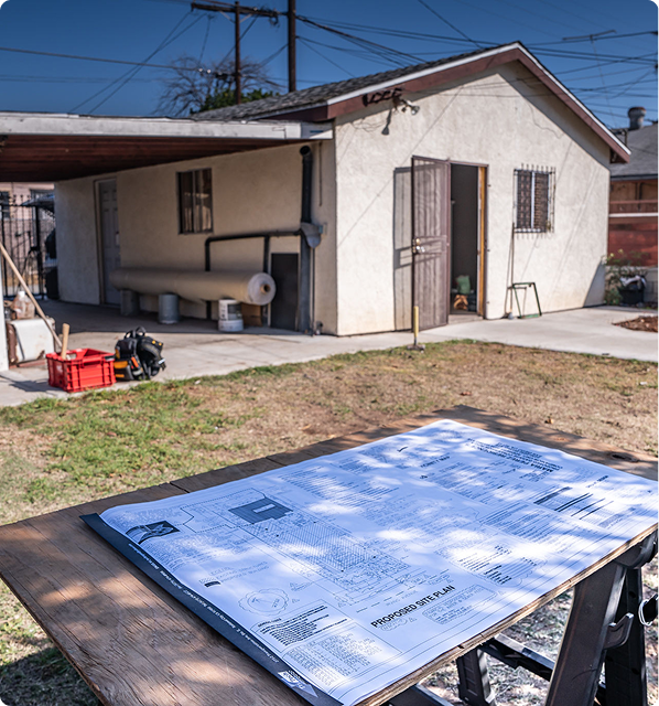 Blueprints on table in backyard construction site.
